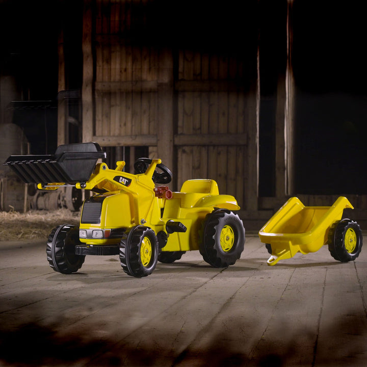 Lifestyle image of the CAT Kid Tractor and trailer in a barn.