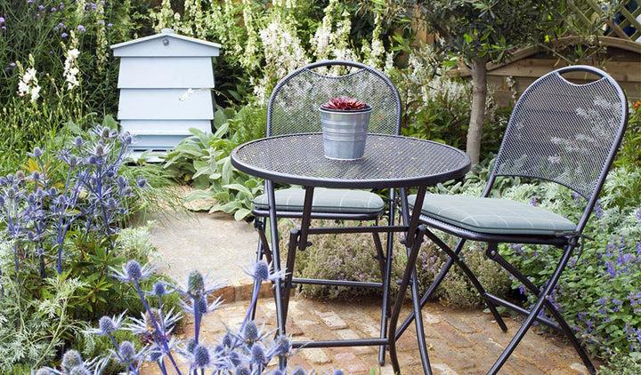 Lifestyle image of drop ship wrought iron set in garden