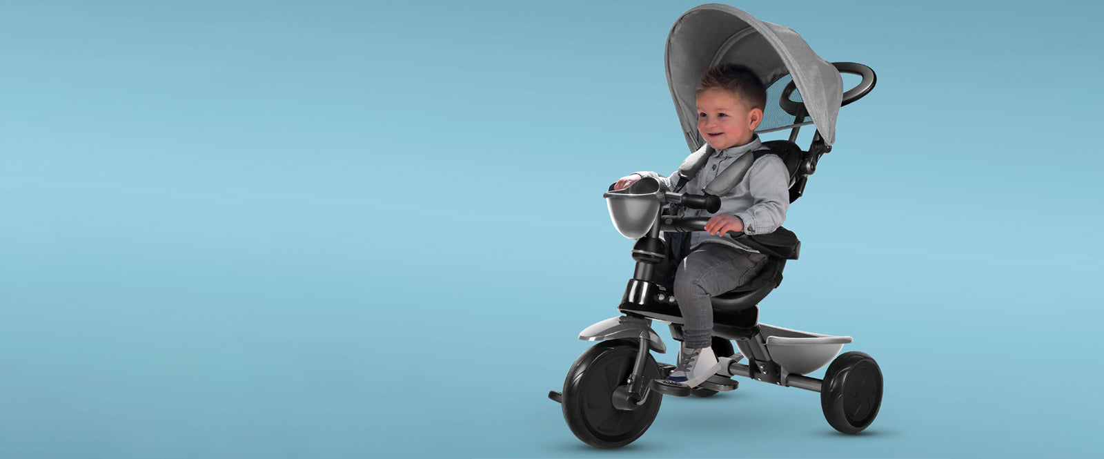 Little boy riding on a Kettler Happy Navigator 4 in 1 tricycle.