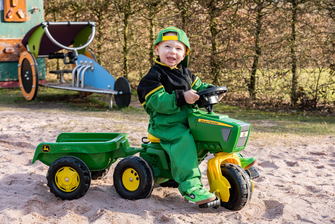 Lifestyle shot of toddler riding John Deere made in Germany three wheel ride on pedal tractor with trailer 