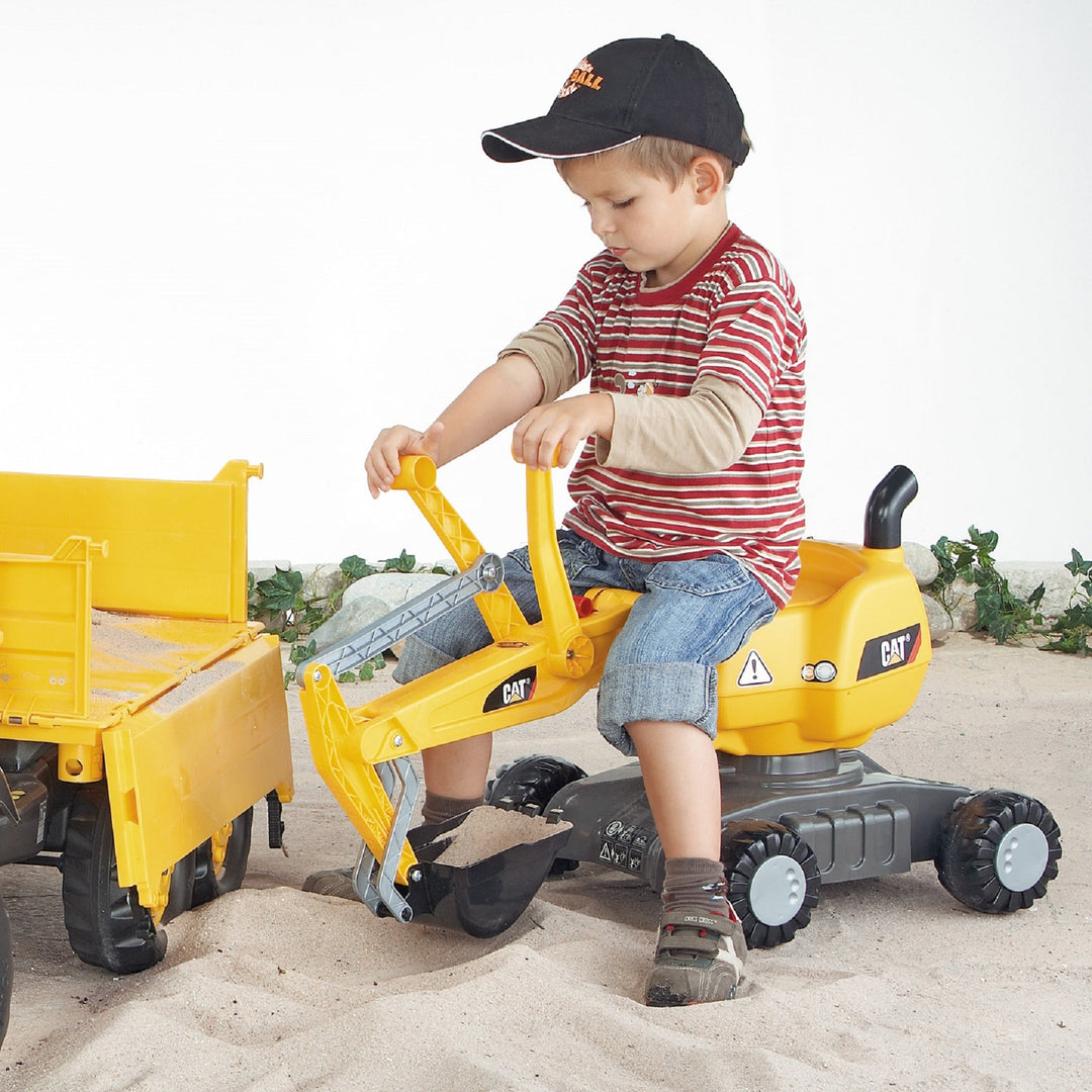 Lifestlye shot of child using Caterpillar digger to scoop sand into trailer 