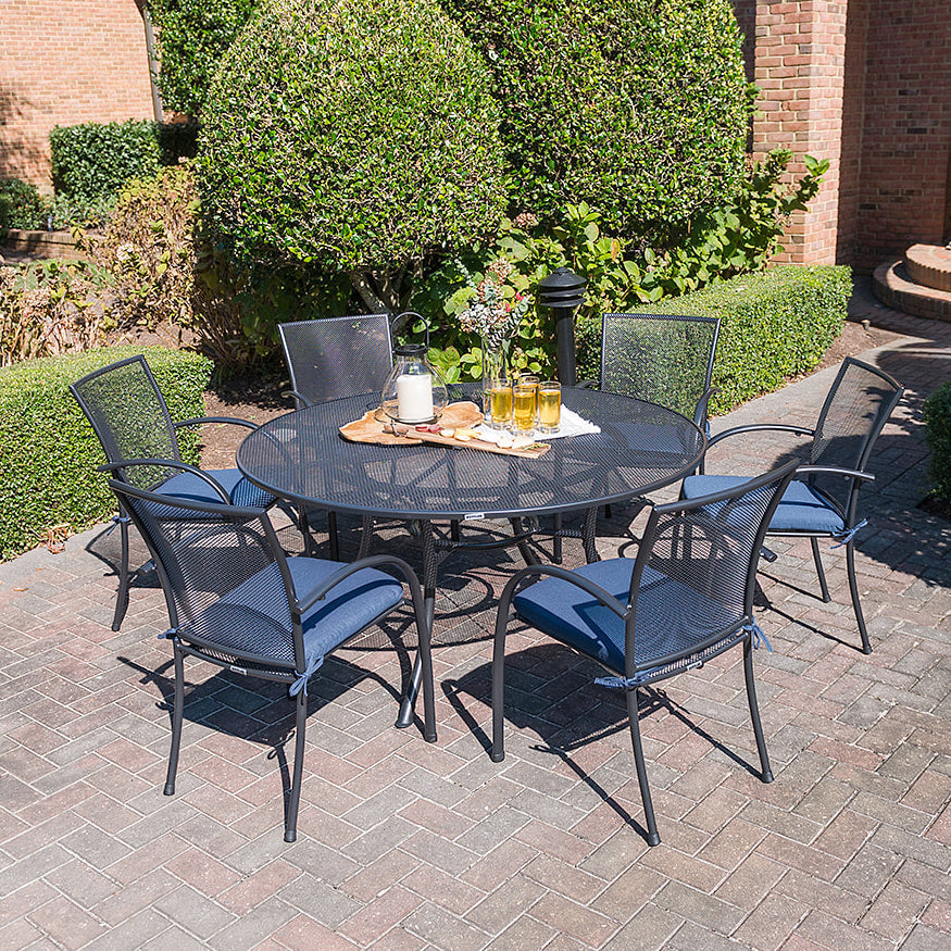 Lifestyle image of the KETTLER 60" round wrought iron mesh dining table with six chairs.