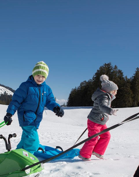 Lifestyle image of two children carrying sleds 